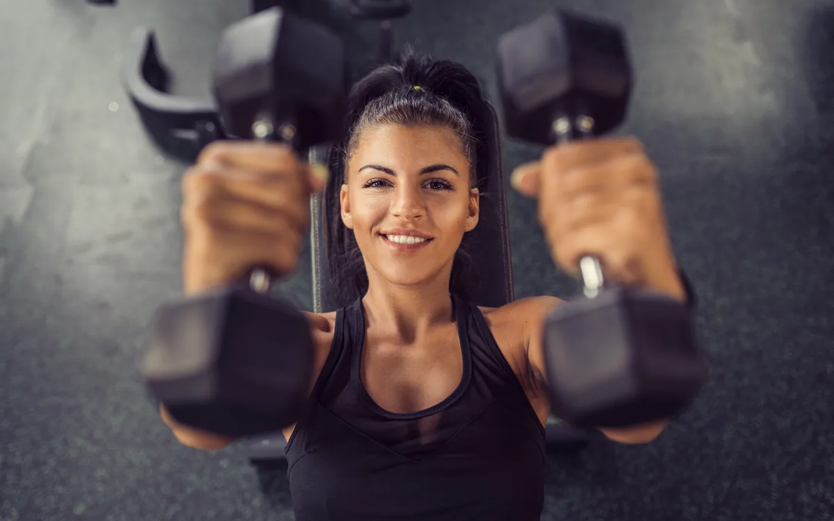 Mulher treinando musculação com halteres no Studio Livel — treino supervisionado